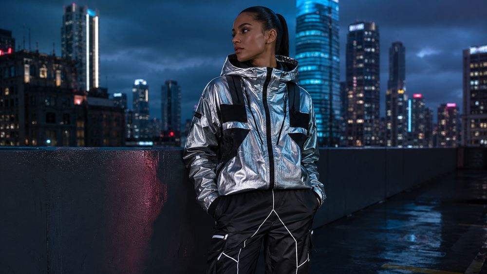 Model wearing metallic futuristic streetwear jacket on a neon-lit city rooftop at night