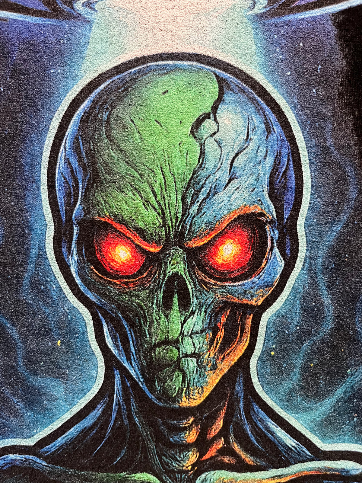 Extreme close-up of the green alien face and glowing red eyes on the Alien Signal tee