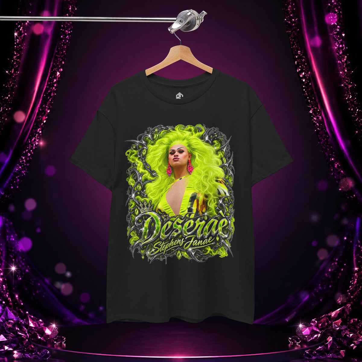 Black Deseraè Stephens Janaè Neon Majesty Portrait Tee hanging on a hanger against a purple and pink stage backdrop