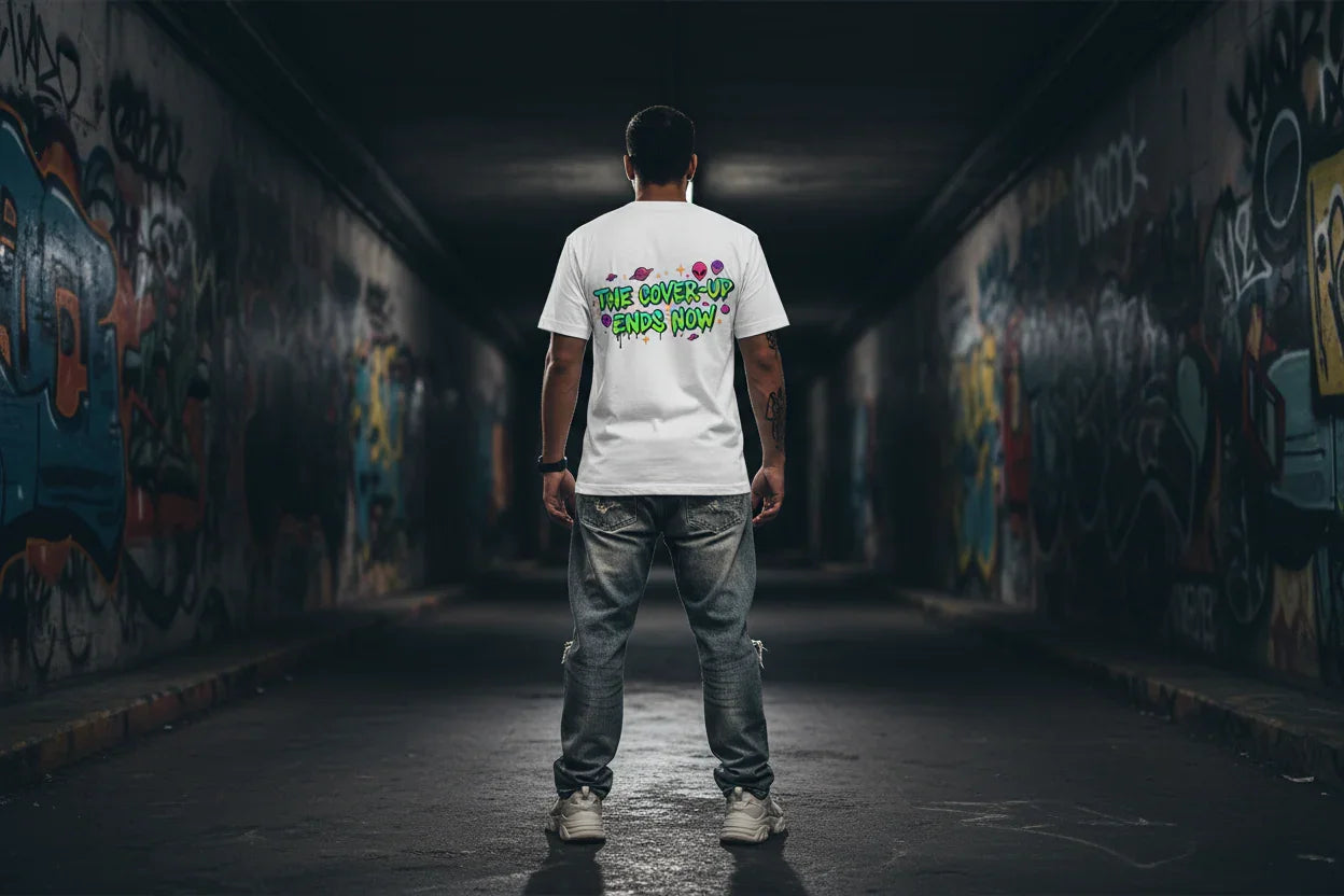 Man in graffiti tunnel wearing white streetwear t-shirt with 'The Cover-Up Ends Now' text