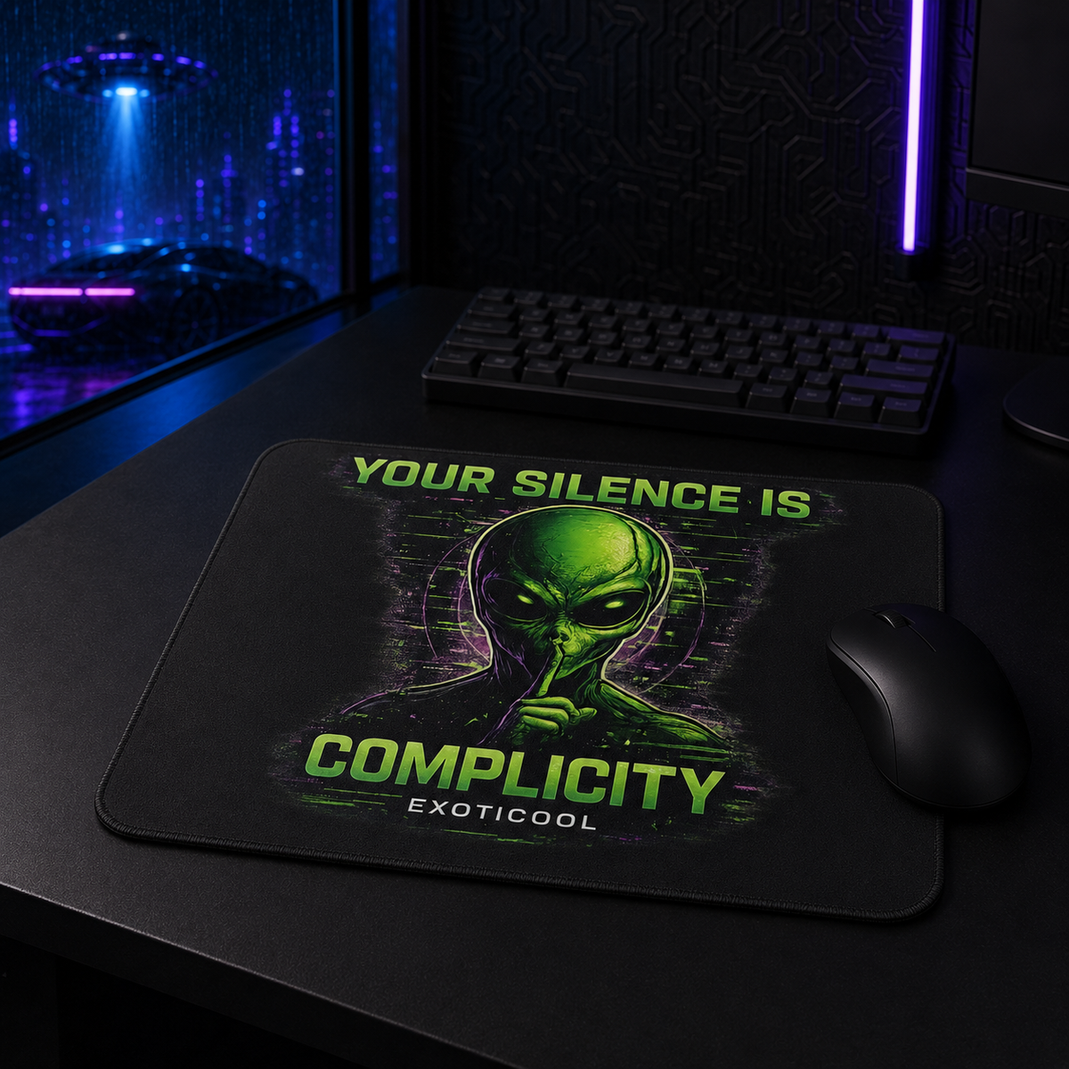 Your Silence Is Complicity alien mouse pad shown with a black mouse and keyboard in a futuristic gaming workstation.

