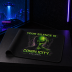 Partially rolled Your Silence Is Complicity alien mouse pad displayed on a boutique counter with the full design visible.