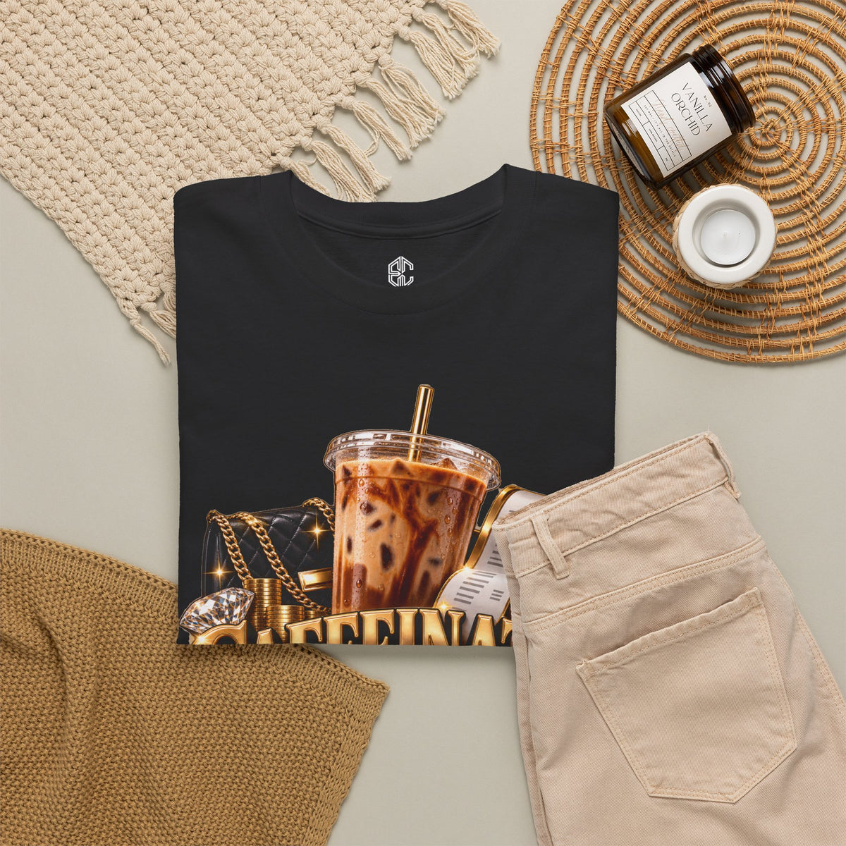 Caffeinated & Compensated black graphic T-shirt styled flat with iced coffee and workday accessories