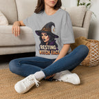 Seated model wearing the Resting Witch Face Halloween graphic tee in sport gray