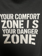 Close-up of Your Comfort Zone Is Your Danger Zone text on the back of the black tee
