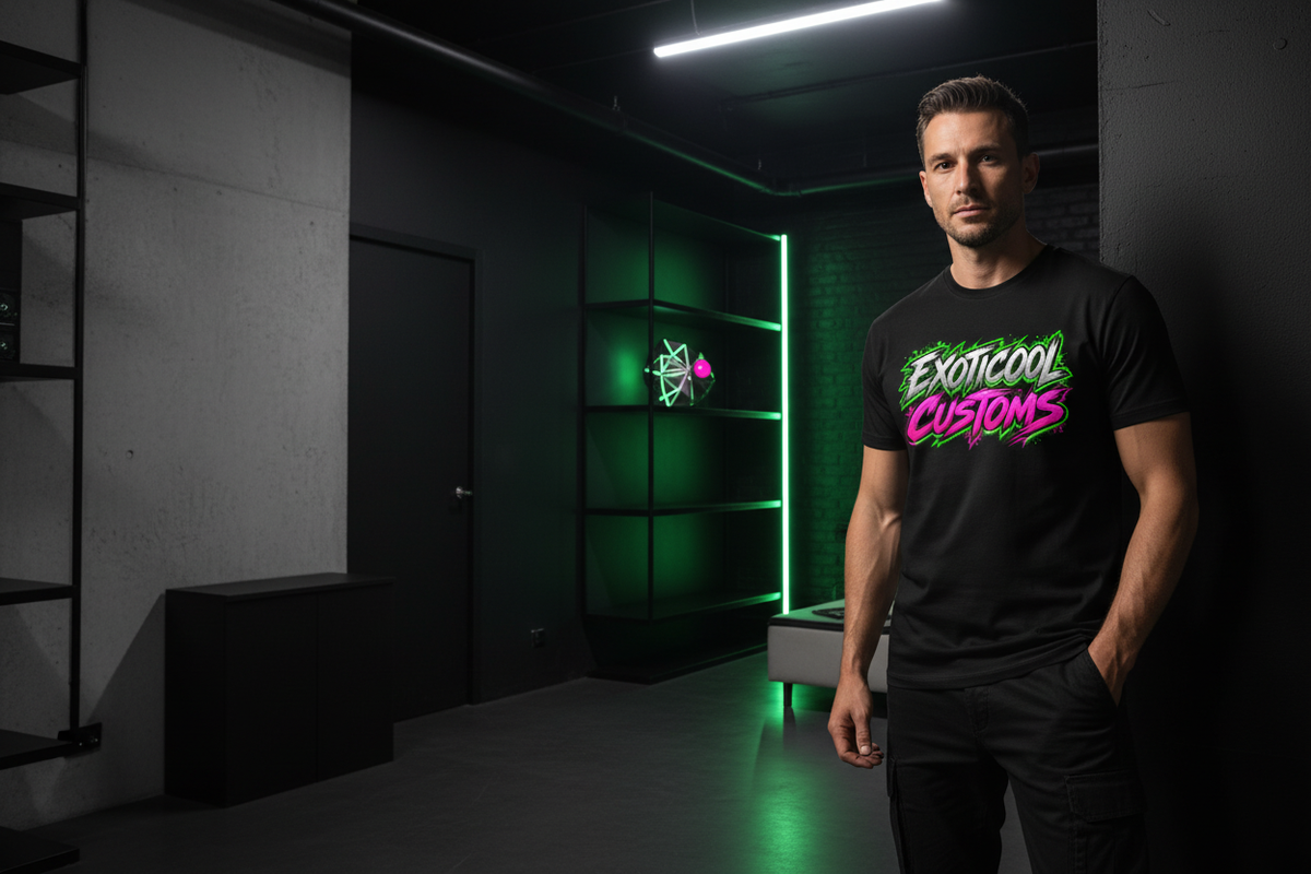 Male model wearing a black Exoticool Customs graphic T-shirt in a dark industrial studio with green and magenta accent lighting.
