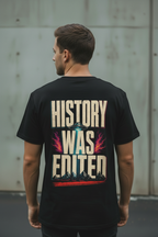 Back view of male model wearing black Exoticool They Were Here First Tee featuring distressed “History Was Edited” UFO graphic in an urban setting
