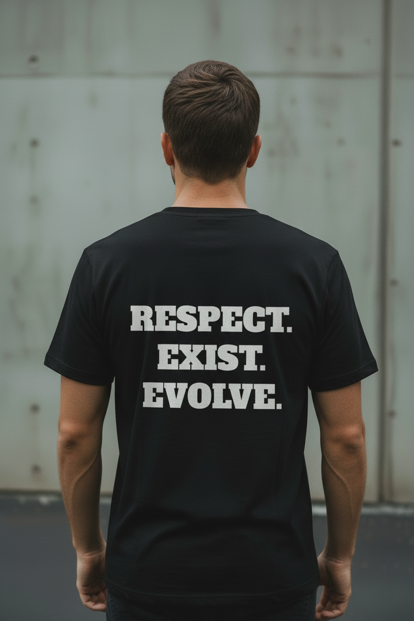 Back view of male model wearing black Exoticool Transphobes Are Trash Tee featuring “Respect. Exist. Evolve.” statement graphic in an urban setting