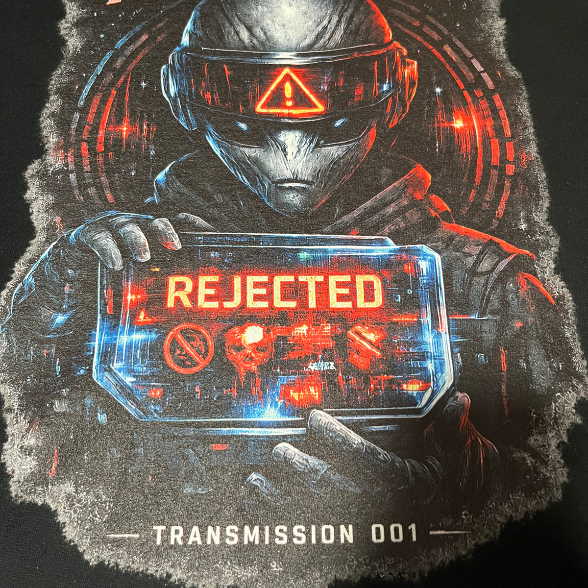 Close-up of Exoticool Transphobes Are Trash tee showing alien figure, glowing REJECTED screen and red-blue cyberpunk print detail on black fabric