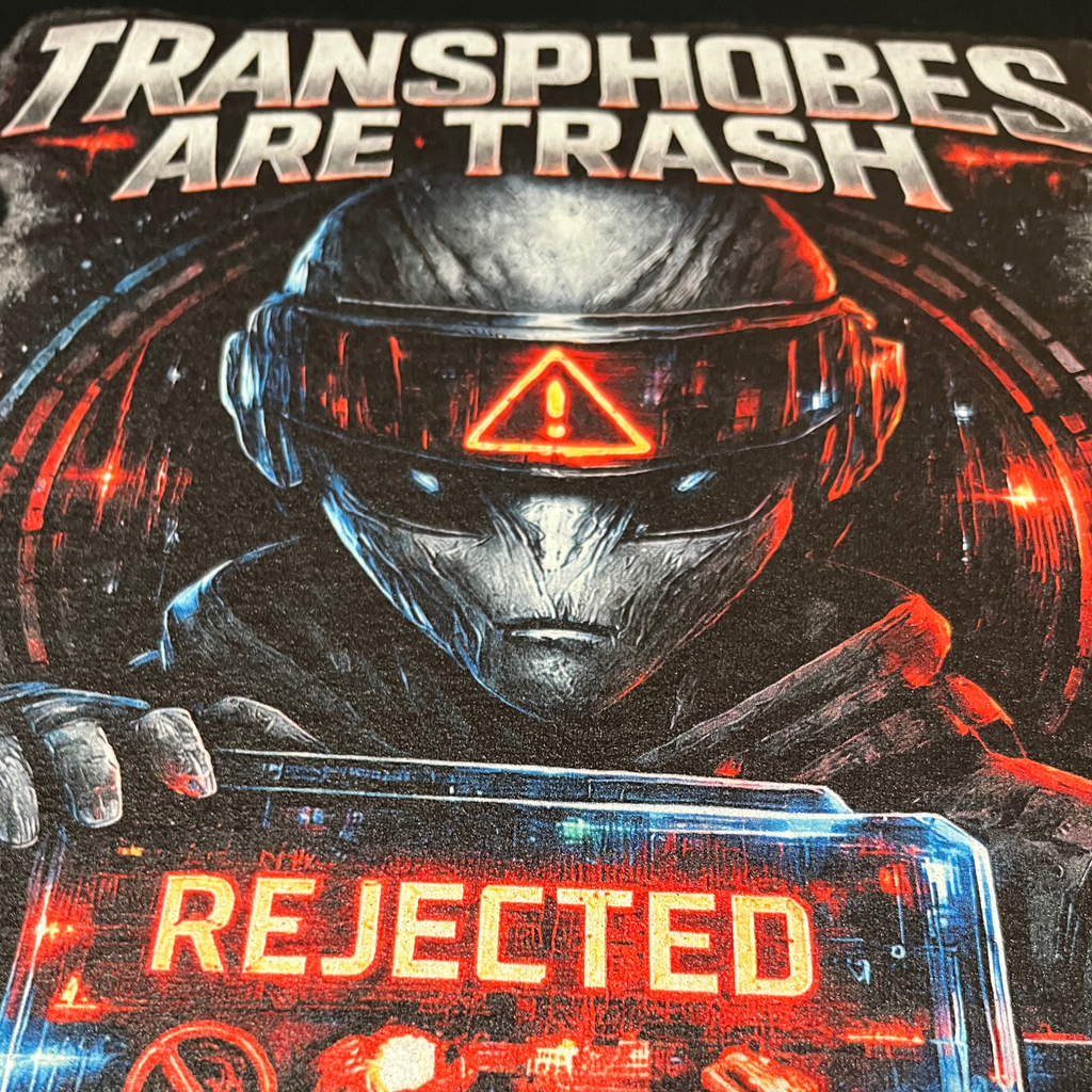 Macro close-up of Transphobes Are Trash graphic showing alien visor, REJECTED message and detailed red, blue and white DTG ink on black fabric